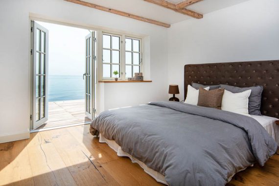 Denne bolig er unik. Hvem ville ikke elske at sove med åbne døre direkte ud til vandkanten! Som led i klargøringen af denne bolig til salg, er boligstylingen imidlertid 'det magiske touch', der for alvor få drømmene til at føles meget tæt på. Sengen her er da lige til at hoppe i.