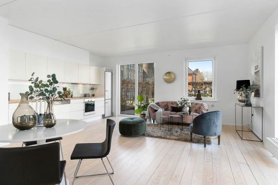 Boligstylingen ved salg af denne lejlighed, åbner boligen op for de potentielle købere – her med et frit udsyn gennem køkken-stue-alrum ud mod terrassen.