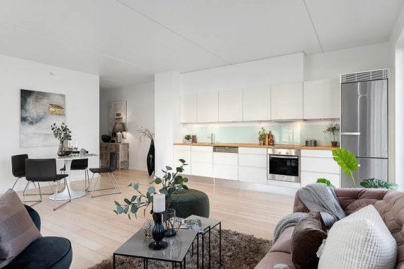 Et godt foto til annoncering ved salg – af hvordan køkken og stue er samlet i et skønt alrum med direkte udgang til terrassen. Boligstylingen af lejligheden på Frederiksberg C præsenterer med de mange anvendelsesmuligheder uden at dette rum virker overfyldt.
